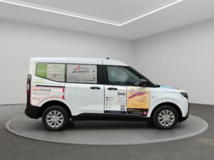 Transporter mit mehreren Werbeflächen steht in einer hellen Halle